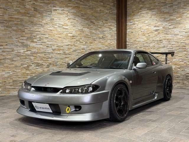 Silver Nissan Silvia S15 with racing modifications and a large rear wing indoors.